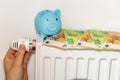 costs of heating apartments in winter in the European Union, energy and economic concept, hand unscrewing the radiator, piggy bank