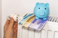 costs of heating apartments in winter in Norway, Energy and economic concept, Hand unscrewing the radiator, piggy bank and a