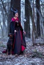 Costume Drama. Charming and Beautiful Maleficent Female with Highbred Dog on Leash. Posing Together in Early Spring Forest