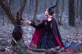 Costume Drama. Charming and Mysterious Maleficent Female with Angry Highbred Dog on Leash. Posing Together in Early Spring Forest