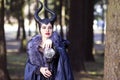 Costume Drama. Young caucasian Female Poses in Maleficent Clothing in Spring Forest