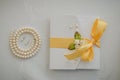 Costume jewelry for the bride: earrings and beads made of artificial pearls. Wedding invitation with yellow satin ribbon and Royalty Free Stock Photo
