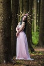 Costume Play Concepts. Sexy and Sensual Crowned Forest Nymph with Flowery Golden Crown Posing in Empty Summer Forest Against High