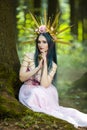 Costume Play. Magnificent Crowned Forest Nymph with Flowery Golden Crown Posing in Summer Empty Forest with Green Background