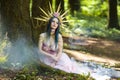 Costume Play. Magnificent Crowned Forest Nymph with Flowery Golden Crown Posing in Summer Empty Forest with Smoky Background