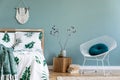 Cosy, boho bedroom interior with wooden bed and white armchair. Royalty Free Stock Photo