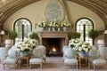 Cosy in light colors living room with fireplace and chairs for reception of guests. Decorated with tables with white flowers Royalty Free Stock Photo