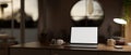 A cosy, modern home workspace at night with a white-screen laptop computer mockup on a wooden desk Royalty Free Stock Photo