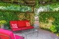 Cosy outdoor living space - Red outdoor furniture on patio under a leafy arbor with ceiling fans and vine covered partial walls