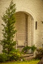 Cosy porch with arch on painted brick vintage home with old fashioned wooden rocking chair and tin tub with fern Royalty Free Stock Photo