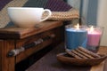 Cosy scene of chocolate biscuits, coffee, candles and wooden chair, rustic feeling