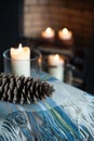 Cosy tartan blanket near fire place with lit candles and pinecone Royalty Free Stock Photo