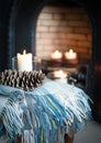 Cosy tartan blanket near fire place with lit candles and pinecone Royalty Free Stock Photo