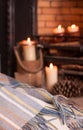 Cosy tartan blanket near fire place with lit candles and pinecones Royalty Free Stock Photo