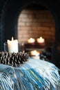 Cosy tartan blanket near fire place with lit candles and pinecone Royalty Free Stock Photo