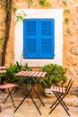 Cosy terrace place with chairs and table and blue window shutter of mediterranean house Royalty Free Stock Photo