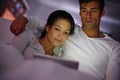 Cosy time has arrived. Cropped shot of a couple watching movies on a digital tablet while sitting in bed. Royalty Free Stock Photo