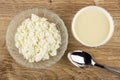 Cottage cheese in bowl, bowl with condensed milk, spoon on wooden table. Top view Royalty Free Stock Photo