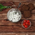 Cottage cheese in bowl of glass, cherry tomatoes, dill and bread