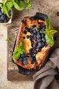 Cottage cheese casserole with blueberries and mint leaves deciration in baking dish on brown rustic textured background