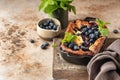 Cottage cheese casserole with blueberries and mint leaves deciration in baking dish on brown textured background with