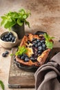 Cottage cheese casserole with blueberries and mint leaves deciration in baking dish on brown textured background