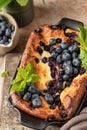 Cottage cheese casserole with blueberries and mint leaves deciration in baking dish close up on brown textured