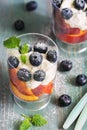 Cottage cheese cream with blueberry berries and peach slices close-up. Delicious dessert with berries on a green wooden rustic tab