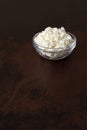 Cottage cheese crumbly in a glass bowl on a wooden old brown tabletop Royalty Free Stock Photo