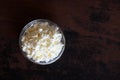Cottage cheese crumbly in a glass bowl on a wooden old brown tabletop top view Royalty Free Stock Photo