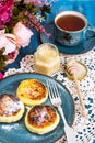 Cottage cheese fritters, honey and tea in a vintage cup on a blu