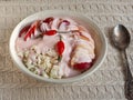 Cottage cheese with fruit and sour cream in a white deep plate on a white knitted tablecloth with rose hips