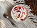 Cottage cheese with nectarines and sour cream in a white deep plate with rosehip fruit on a white knitted tablecloth, teaspoon