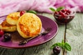 Cottage cheese pancakes on a dark background. Syrniki with fresh mint. Pancakes with cottage cheese on a lilac plate