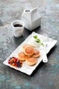 Cottage cheese pancakes, fritters or syrniki served with berries and sour cream on a white plate