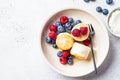 Cottage cheese pancakes with raspberries, blueberries and syrup in white bowl, gray background. Russian cuisine concept Royalty Free Stock Photo