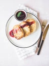 Cottage cheese pancakes Russian syrniki with cherry jam served on a white plate with black and gold appliances. Top view. Copy