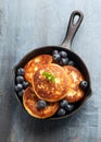 Cottage cheese pancakes served in cast iron frying pan with blueberries and mint leaves. Healthy breakfast food. Royalty Free Stock Photo