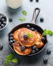 Cottage cheese pancakes served in cast iron frying pan with blueberries and mint leaves. Healthy breakfast food. Royalty Free Stock Photo