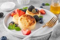 Cottage cheese pancakes, syrniki, ricotta fritters with fresh berries, honey and sour cream on a gray concrete background. Healthy Royalty Free Stock Photo