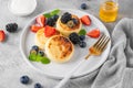 Cottage cheese pancakes, syrniki, ricotta fritters with fresh berries, honey and sour cream on a gray concrete background. Royalty Free Stock Photo