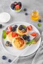 Cottage cheese pancakes, syrniki, ricotta fritters with fresh berries, honey and sour cream on a gray concrete background. Royalty Free Stock Photo