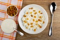 Cottage cheese with sour cream, raisin in plate, napkin, bowls with raisin, sour cream on napkin, spoon on table. Top view Royalty Free Stock Photo