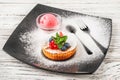 Cottage cheese tart with fruits in a restaurant close-up. Cupcake with strawberries, mint, blueberries on a black plate and copy s Royalty Free Stock Photo