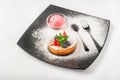 Cottage cheese tart with fruits in a restaurant close-up. Cupcake with strawberries, mint, blueberries on a black plate and copy s Royalty Free Stock Photo