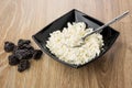 Cottage cheese and teaspoon in black bowl, heap of prunes