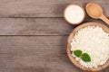 Cottage cheese in a wooden bowl with sour cream on old wooden background with copy space for your text. Top view Royalty Free Stock Photo