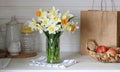 Cottage core. A table with dishes, a bouquet of daffodils and apples in the kitchen with a white interior. Royalty Free Stock Photo