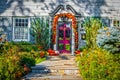 Cottage with pretty entranceway decorated for Autumn-Harvest_Thanksgiving with leaf garland and pumpkins - pretty landscaping