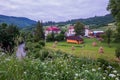 Cottages for recreation on a green meadow with haystacks in a mountain valley against the backdrop of green mountain Royalty Free Stock Photo